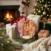 Rose-red Petra Christmas ornament arranged beside wrapped holiday gifts near a warm glowing fireplace.