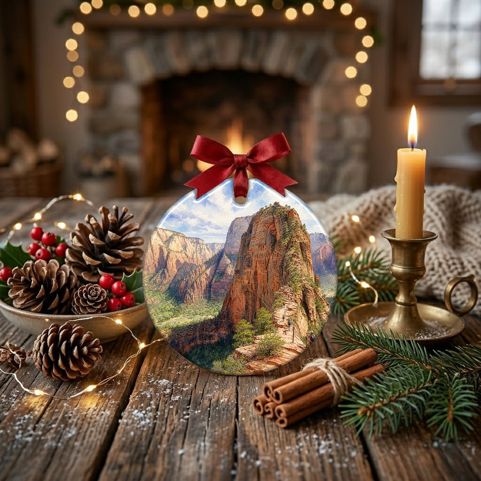 Holiday tabletop display with the ceramic Angels Landing ornament set beside pinecones and a warm candle.