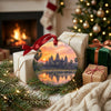 Holiday travel ornament arranged alongside wrapped seasonal gifts near a warm glowing fireplace.