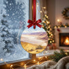 Round desert souvenir ornament suspended before a frosty winter window in bright daylight.