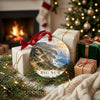 Ceramic Pacific coast road trip ornament resting near wrapped holiday gifts in front of a warm glowing fireplace.