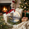 Festive New York ornament sitting beside wrapped gifts near a warm fireplace.