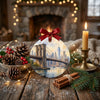 Round ceramic holiday ornament placed on a table beside seasonal pinecones.