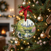 Ceramic travel keepsake hanging from a holiday tree branch with warm lights.