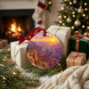 Southwest landscape ornament resting beside festive wrapped gifts near a glowing warm fireplace.