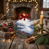 Holiday ceramic ornament styled on a rustic table with decorative pinecones and candles.