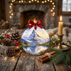 Holiday keepsake resting on a holiday table surrounded by pinecones and a warm glowing candle.