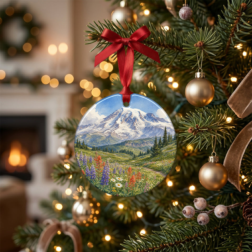 Ceramic mountain holiday keepsake hanging from the pine branch of an illuminated Christmas tree.