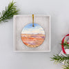 Round ceramic holiday keepsake nestled inside an opened white gift box ready for gifting.