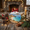 Pink Beach Christmas keepsake styled on a rustic holiday table next to a natural pinecone and candle.