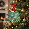 Ceramic Plitvice Lakes holiday ornament hanging from a festive Christmas tree branch.