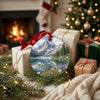 Festive mountain landscape ornament placed beside wrapped holiday gifts near a warm glowing fireplace