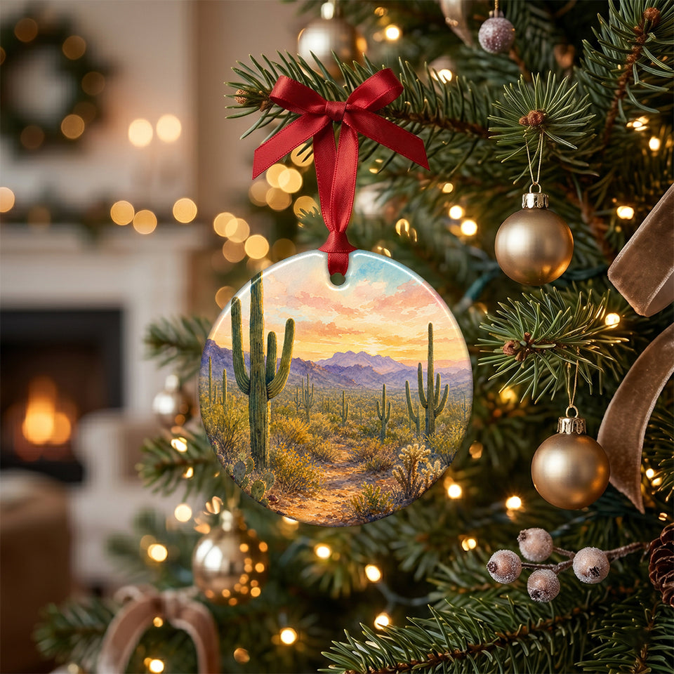 Holiday ornament featuring Sonoran Desert saguaro cacti hanging from a lit Christmas tree branch.